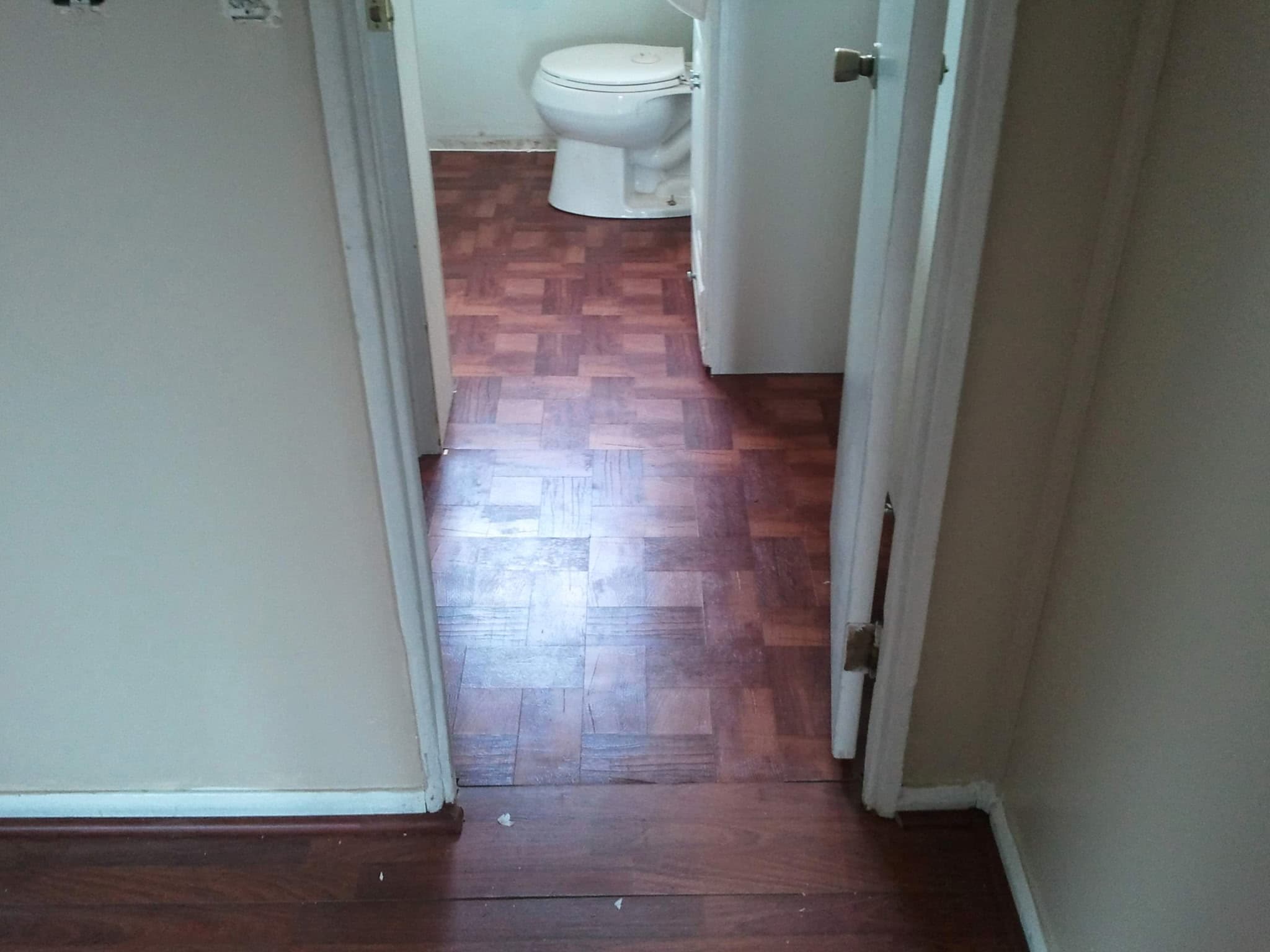 Refinished parquet wood flooring leading into a bathroom