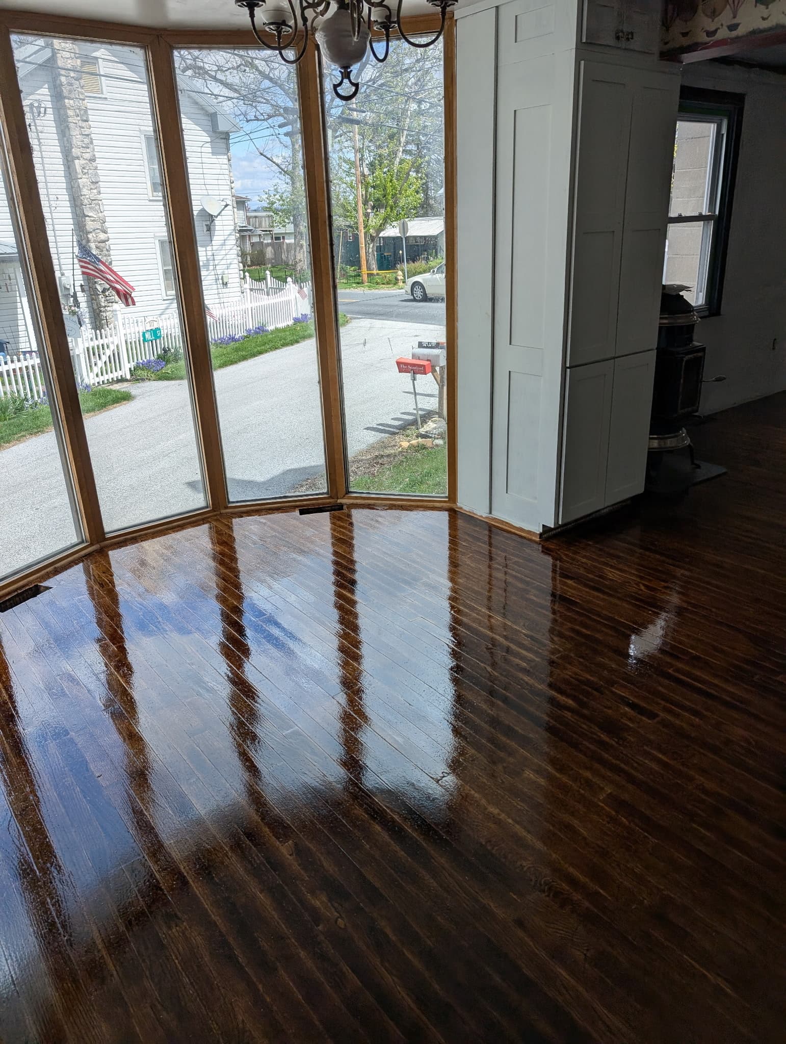 Freshly refinished hardwood floor glowing in a bay-window living room