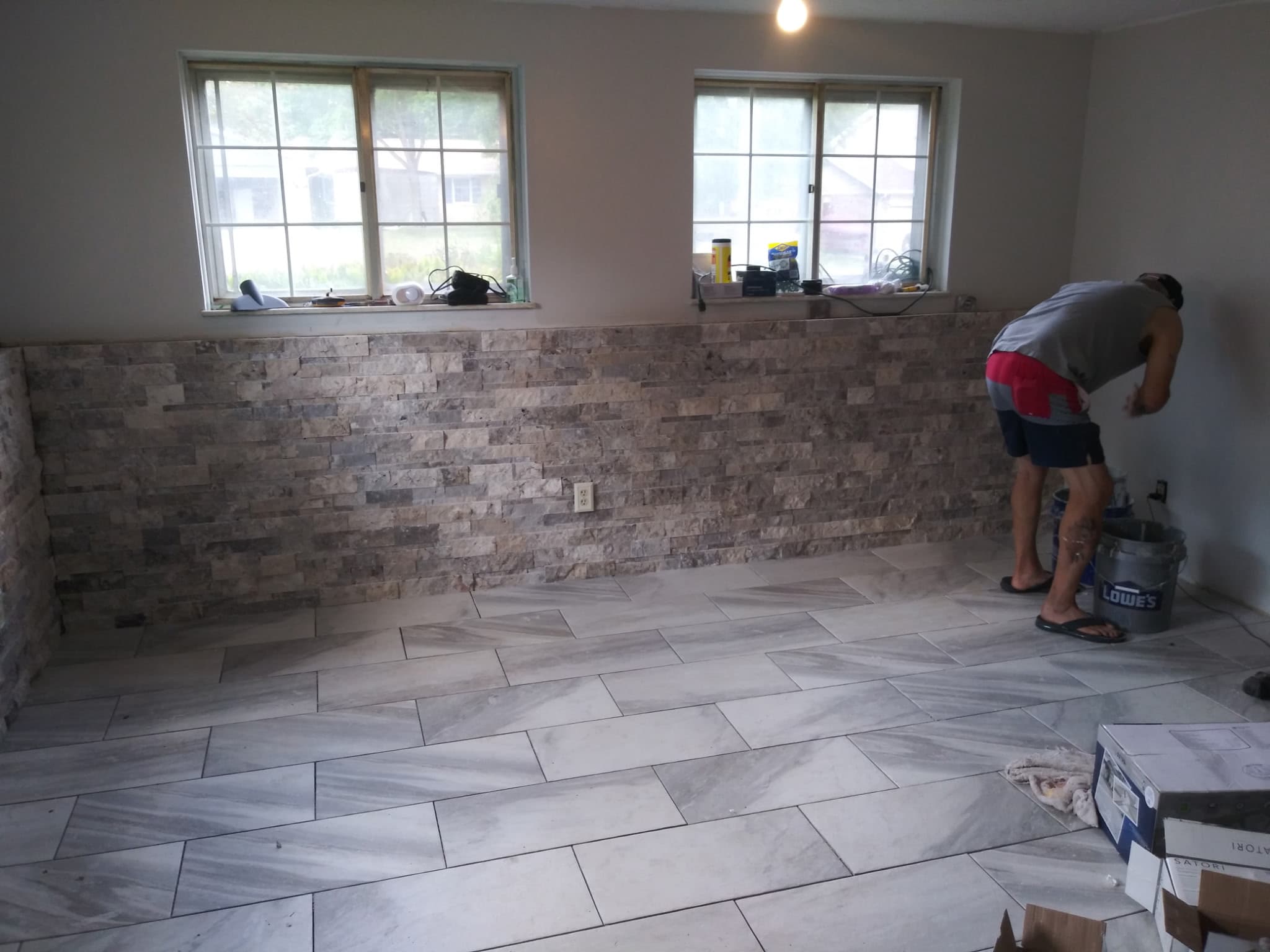 Stacked stone-veneer accent wall above a large-format tile floor