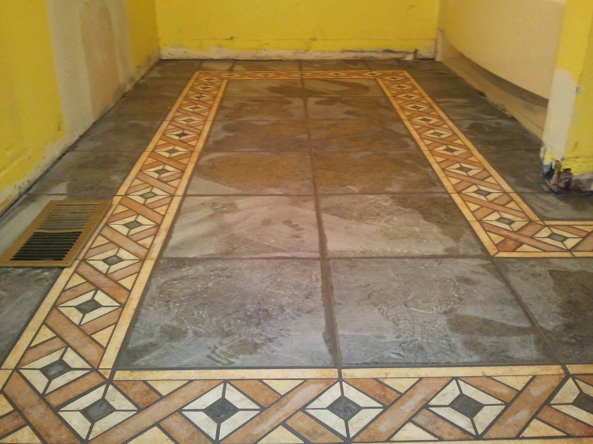 Tile floor with a hand-set decorative mosaic inlay border